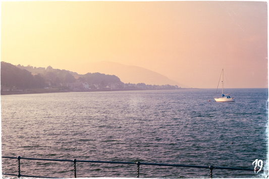 Sailboat on a calm sea with a sunset or sunrise sky